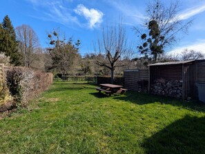 A grassy yard with a picnic table, a wooden shed, and a stack of firewood. - Cottage by the Creuse with private parking in Ceaulmont (Ceaulmont)