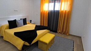 A hotel room with a bed, bedside tables, a bench, and curtains. - The Infinite (Ribeira Grande)