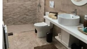 A modern bathroom with a large mirror, two sinks, a toilet, and a shower area. - The Infinite (Ribeira Grande)