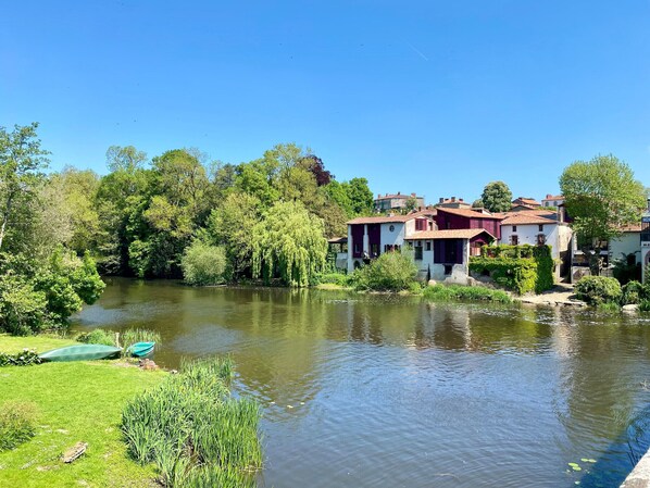 A riverside view with traditional buildings, a boat, and lush greenery.