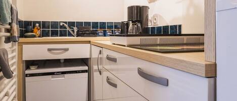 A modern kitchen with white cabinets, a built-in dishwasher, and a coffee machine.