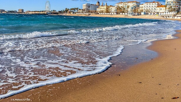 A beach with waves, a Ferris wheel, and buildings in the background. - Bright 2-room apartment, air-conditioned, near the sea in Saint-Raphaël (Saint-Raphaël)