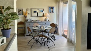 A dining area with a table set for four, surrounded by wicker chairs. There is a buffet counter with a lamp and a painting above it. - Bright 2-room apartment, air-conditioned, near the sea in Saint-Raphaël (Saint-Raphaël)