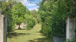 A pathway leading through a lush, green area with a metal gate on the right. - Provençal villa with garden and parking for 4 near Riez center (Riez)