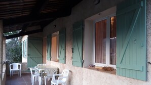 A covered patio with a table and chairs, a window with shutters, and a door. - Provençal villa with garden and parking for 4 near Riez center (Riez)