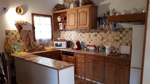 A kitchen with a tiled backsplash, wooden cabinets, a central island, and various kitchen appliances. - Provençal villa with garden and parking for 4 near Riez center (Riez)