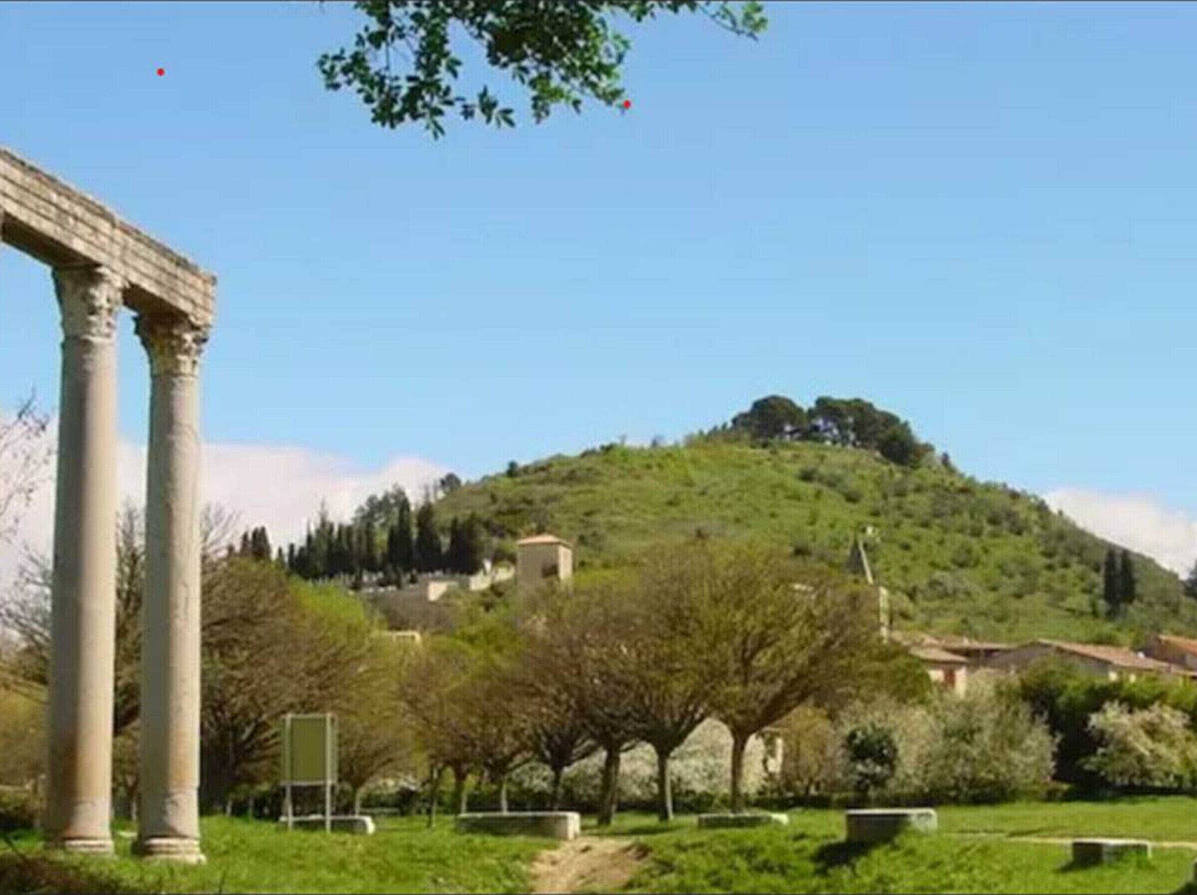 Un site historique doté d’anciennes colonnes et d’une colline en arrière-plan, sur laquelle se dressent des bâtiments.