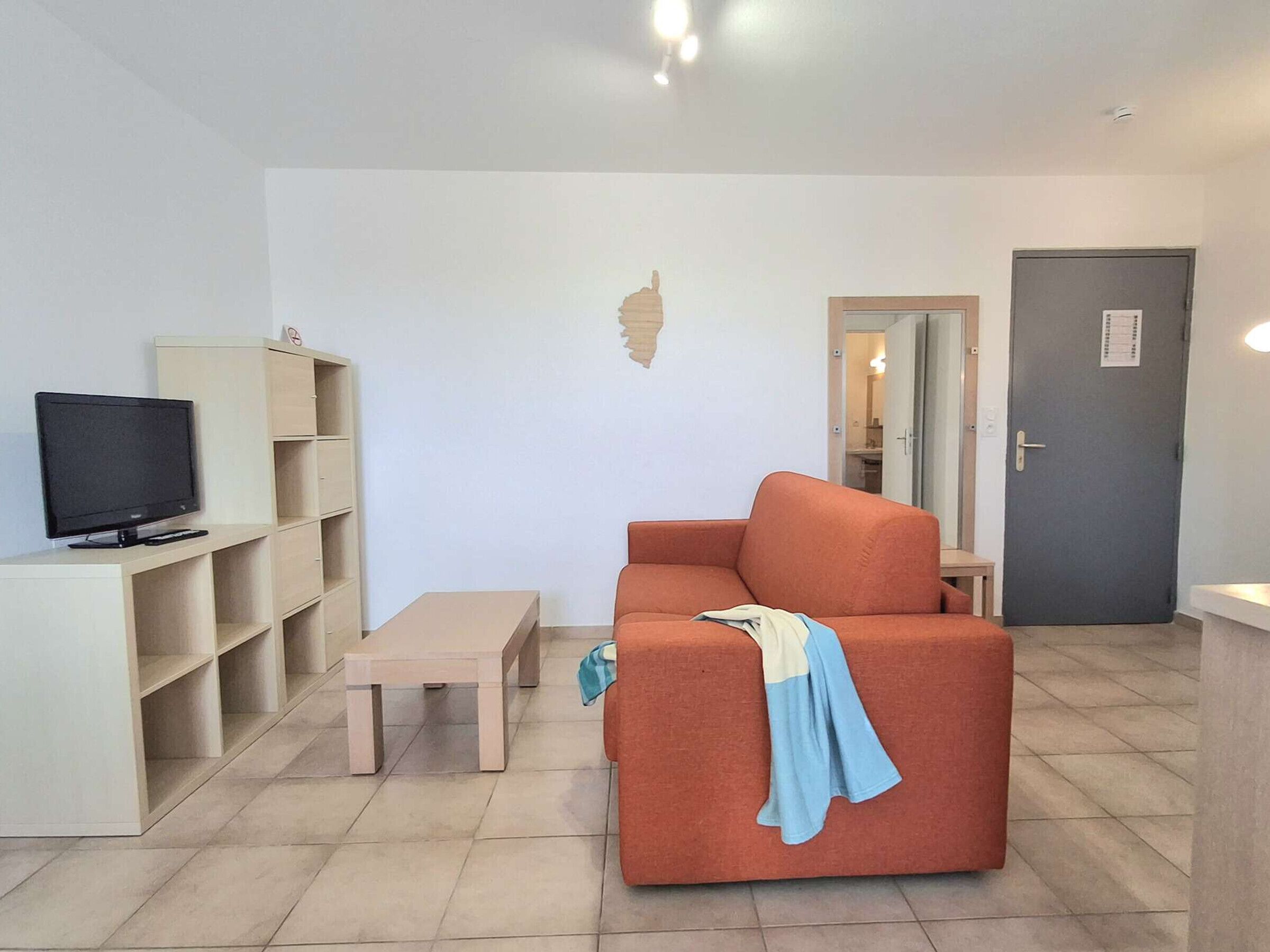 A living room with a television, a sofa, a coffee table, and a bookshelf.