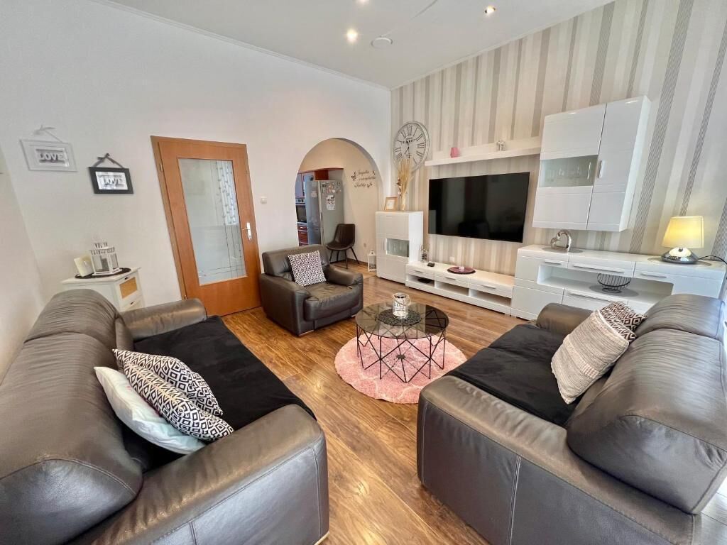 Ein modernes Wohnzimmer mit Ledersofas, einem Fernseher und einem Kamin.