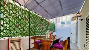 A covered patio with a wooden table and benches, a decorative wall, and a white lantern. - Holiday house Lona (Crikvenica)