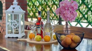 A table with a white lantern, bottles of alcohol, a vase with pink flowers, and a bowl of fruit. - Holiday house Lona (Crikvenica)