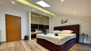 A modern bedroom with a large bed, a sliding door closet, and recessed ceiling lighting. - Holiday house Lona (Crikvenica)