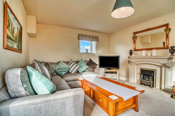 A living room with a sofa, television, fireplace, and a painting on the wall. - Holiday Home in Ashbourne Near Dovedale Trails (Ashbourne)