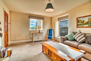 A room with a wooden desk, a sofa, a bench, a radiator, a window with a view, and a painting on the wall. - Holiday Home in Ashbourne Near Dovedale Trails (Ashbourne)