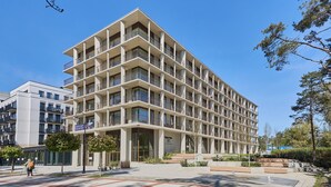Un hotel a più piani con un design architettonico moderno, caratterizzato da balconi su ogni piano e un ingresso centrale.