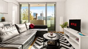 Uma sala de estar moderna com um sofá, uma mesa de centro e uma TV exibindo 'NETFLIX'.