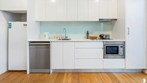 Uma cozinha moderna com armários brancos, lava-louças, micro-ondas e pia.