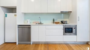 Una cocina moderna con armarios blancos, lavavajillas, microondas y un lavabo.