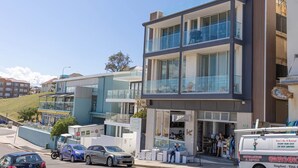 A multi-story building with a glass facade, a cafe on the ground floor, and a sign for 'Kingsford - 9344 6'. - Cozy Beachfront Studio With Aircon (Sydney)
