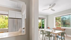 Une cuisine moderne équipée d’appareils électroménagers en acier inoxydable, un coin repas avec une table et des chaises, et une grande fenêtre donnant sur un paysage verdoyant.
