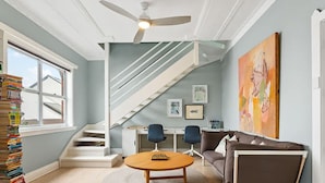 Un salon avec un escalier, un ventilateur, une table et un canapé.