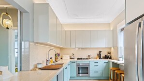 Une cuisine moderne avec des meubles de couleur bleu clair, des appareils en acier inoxydable et un grand îlot central doté de tabourets.