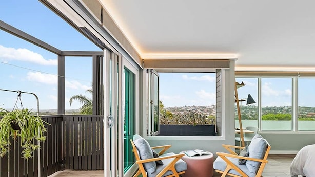 Un balcon moderne offrant une vue sur le paysage urbain, avec un espace salon comprenant deux chaises et une petite table.