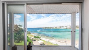 Un balcón con puerta de cristal que da a vista de playa.