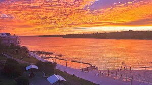 Vista al agua con un atardecer, un paseo marítimo y una costa distante.