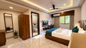 Una habitación de hotel moderna con una cama grande, un escritorio, un televisor y un baño visible a través de una puerta abierta.