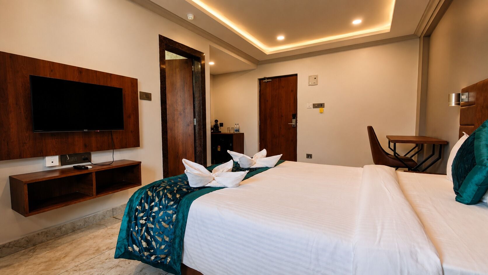 Una habitación de hotel con cama, televisor, escritorio y espejo.