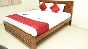 Una cama bien hecha con estructura de madera, ropa de cama roja y blanca, y dos almohadas rojas.