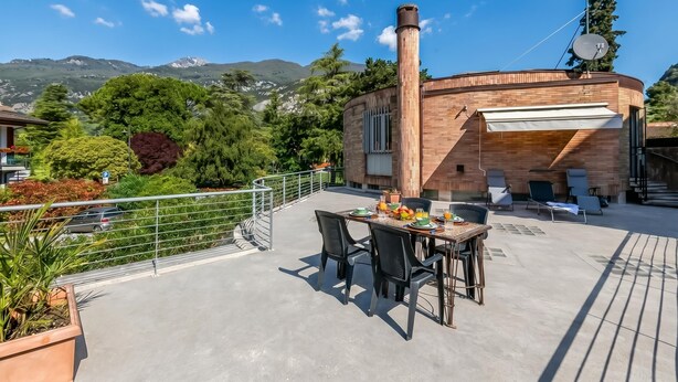 Una terraza en la azotea con mesa lista para comer, sillas de descanso y una chimenea.