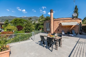 Una terraza en la azotea con mesa lista para comer, sillas de descanso y una chimenea.
