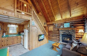 A log cabin interior with a kitchen, living room, and fireplace. - Rough Cut Lodge - Oak Cabin (Gaines)