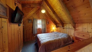 Un dormitorio acogedor en el ático con cama, televisión y ventana con cortinas.