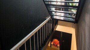 A staircase with a black railing and a white handrail, leading to a door with a decorative floral arrangement. - Chatel Samyan BKK (Bangkok)