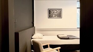 A small, cozy room with a single bed, a wooden chair, and a framed picture on the wall. - Chatel Samyan BKK (Bangkok)