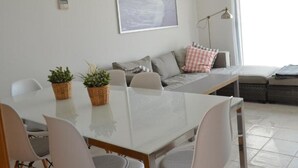 A modern living room with a dining area, featuring a sofa set, a coffee table, and a dining table with chairs. - Macenas 85.2 Apartments (family and pets) (AN)