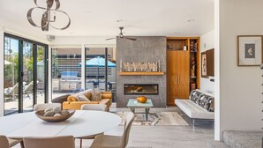Una sala de estar moderna con chimenea, un comedor y una zona de estar con sofá y sillones.