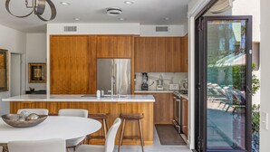 Una cocina moderna con armarios de madera, una isla central y un ventanal que da a una zona de piscina.