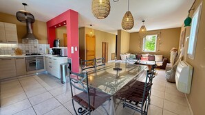 A modern kitchen with a glass dining table, stainless steel appliances, and a red accent wall. - Beachfront villa with pool (Lumio)