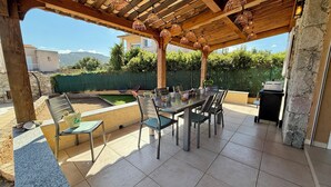 An outdoor patio with a wooden pergola, a dining table with chairs, a barbecue grill, and a small pool area. - Beachfront villa with pool (Lumio)