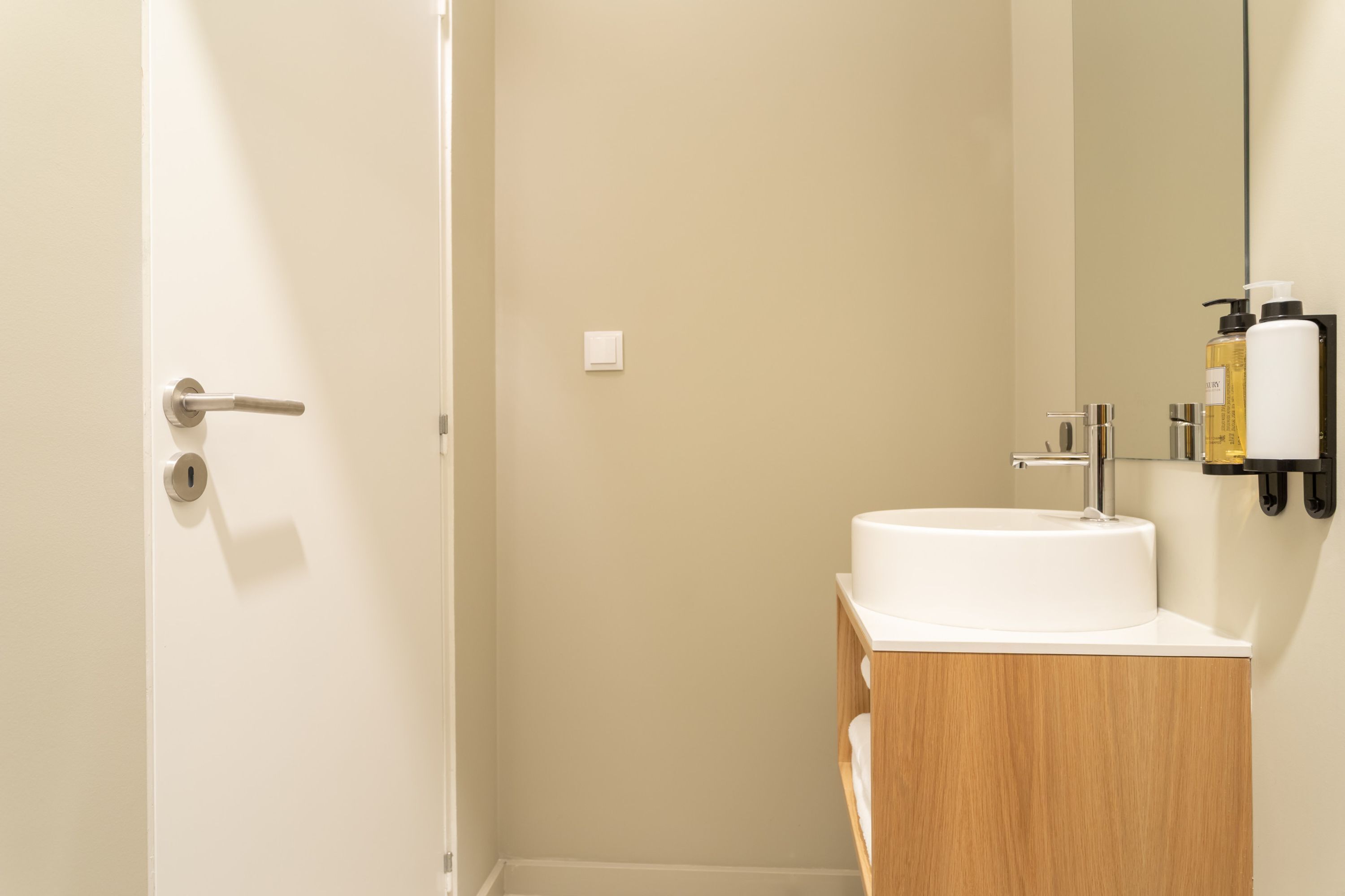 Une salle de bain avec un lavabo blanc, un meuble-lavabo en bois et un miroir.