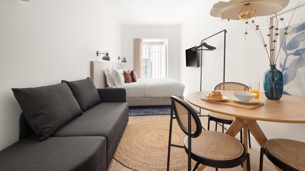 A modern living room with a sofa, dining table, chairs, and a TV. - Lapa Diplomatic Flat 0 4 by Feel Lisboa (Lisbon)