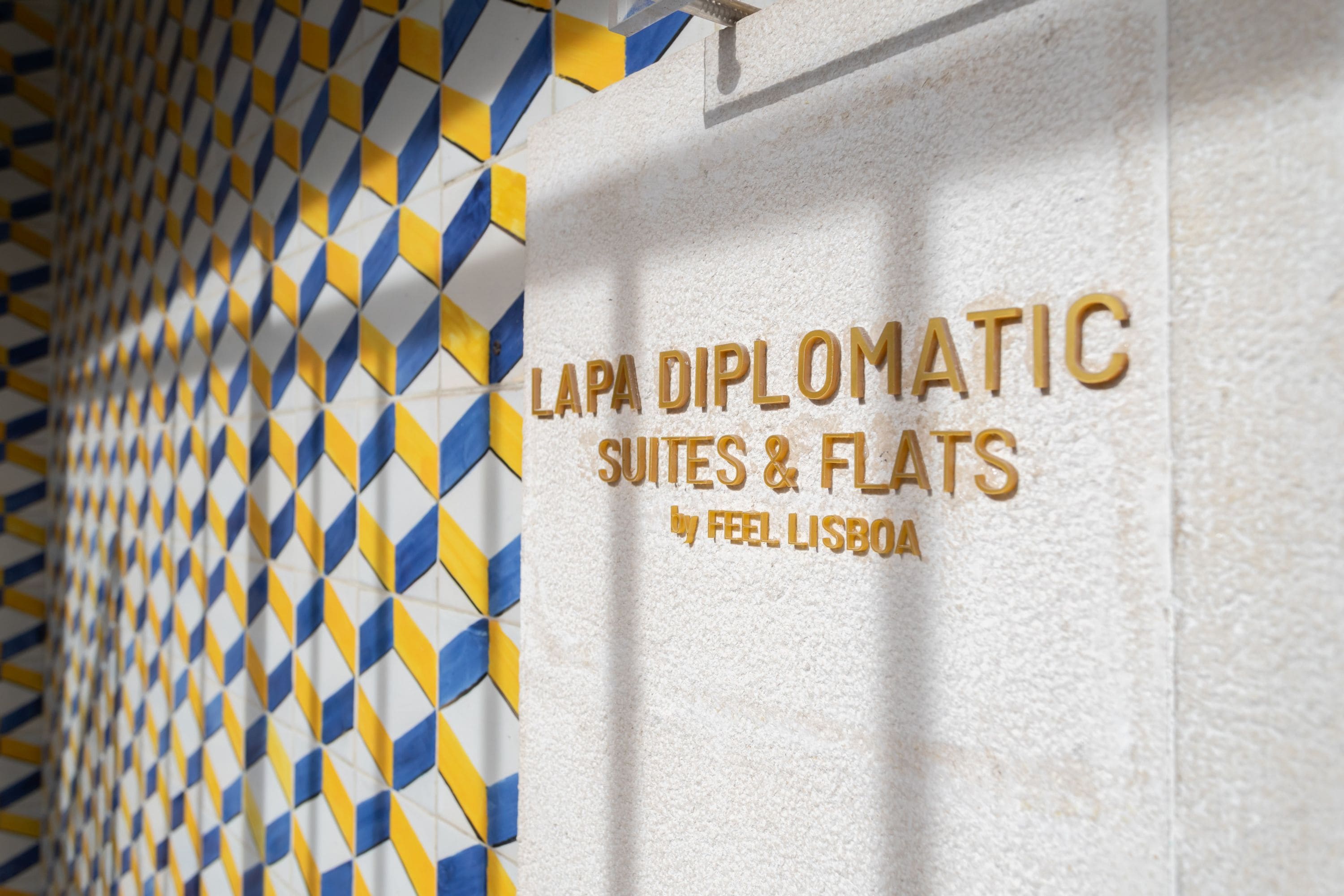 A textured wall with a geometric pattern and the text 'LAPA DIPLOMATIC SUITES & FLATS by FEEL LISBOA'.
