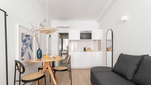 A modern living room with a sofa, dining table, chairs, and a kitchen area in the background. - Lapa Diplomatic Flat 0 4 by Feel Lisboa (Lisbon)