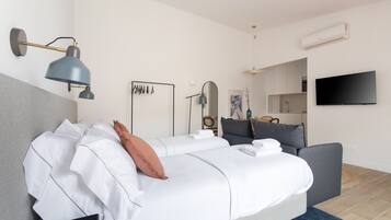 Een moderne hotelkamer met een groot bed, een bureau, een flatscreen televisie en een kitchenette.