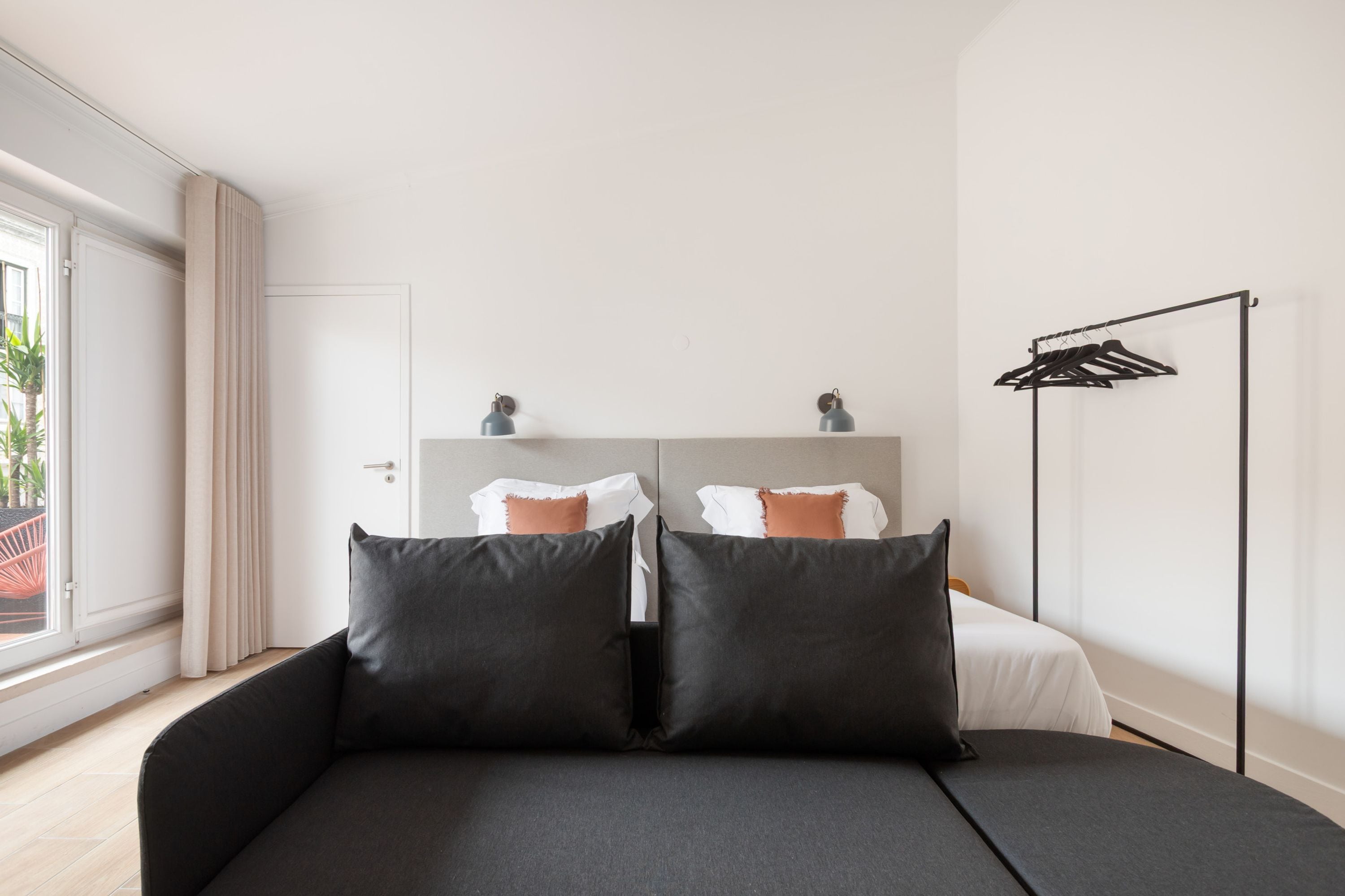 Une chambre moderne avec un canapé-lit, une armoire et une fenêtre avec des rideaux.