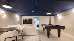 A modern room with a pool table, a sofa, a TV, and a kitchenette. - Lapa Diplomatic Flat 1 1 by Feel Lisboa (Lisbon)